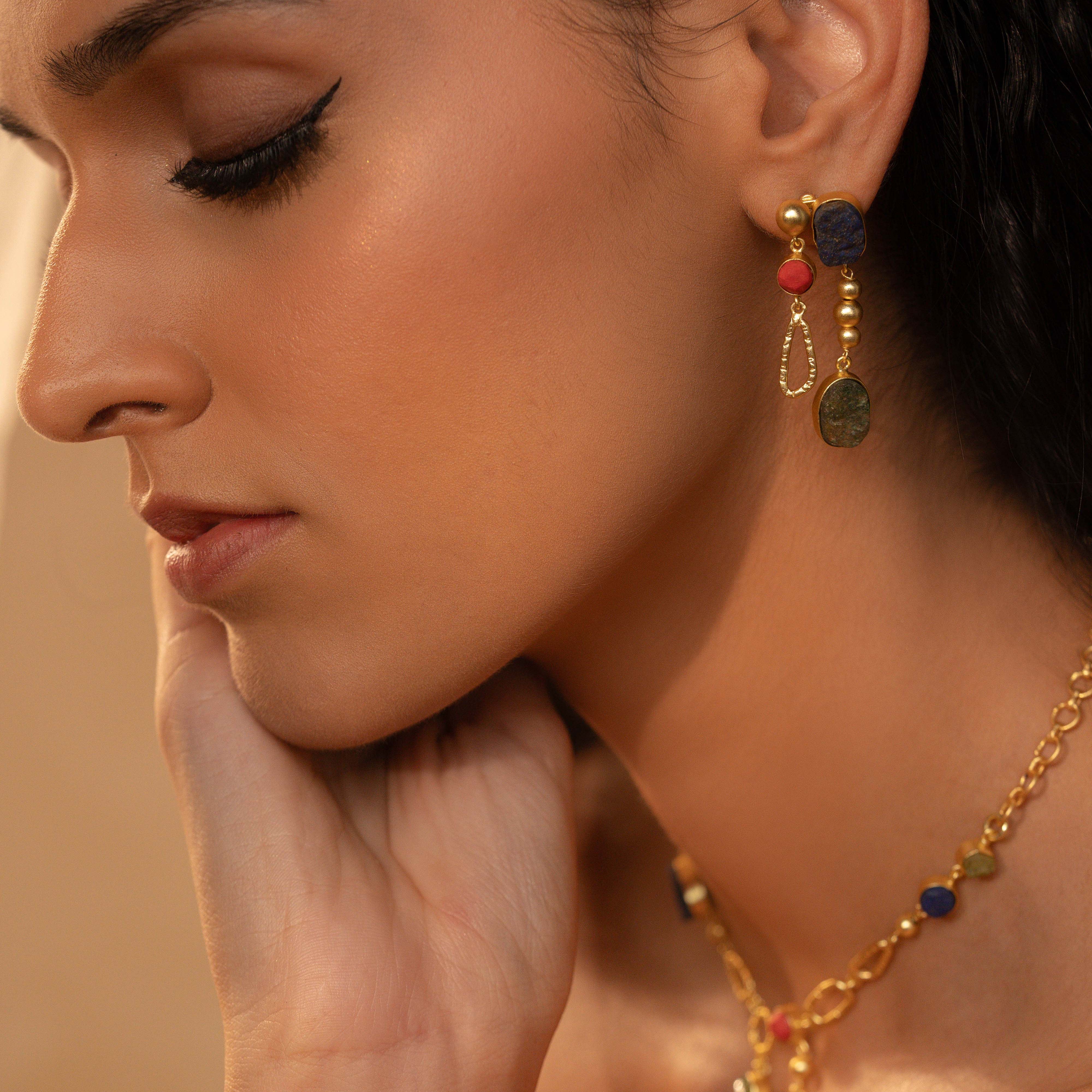 Close-up of a woman wearing gold earrings and a necklace with colorful beads.