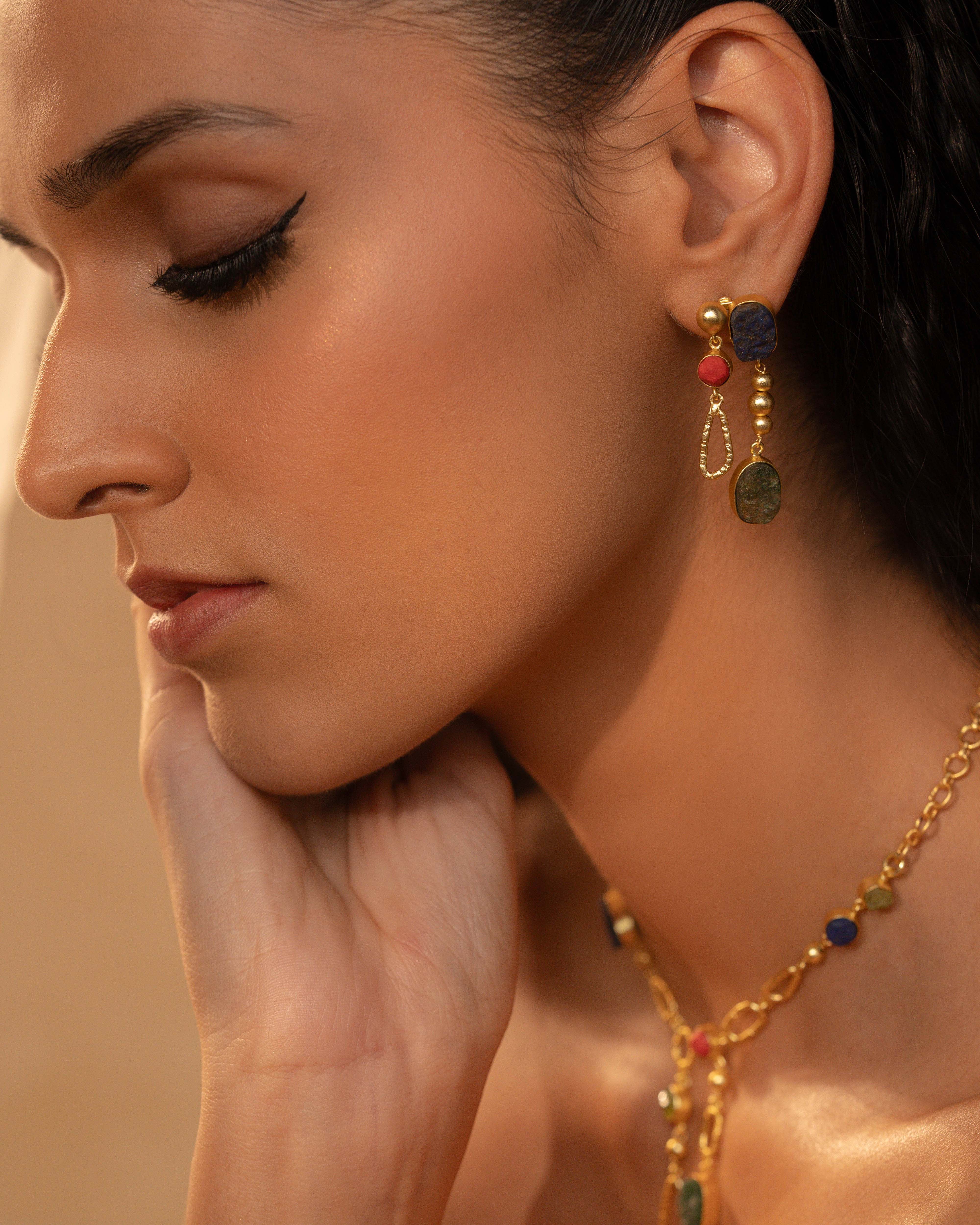 Close-up of a woman wearing gold earrings and a necklace with colorful beads.