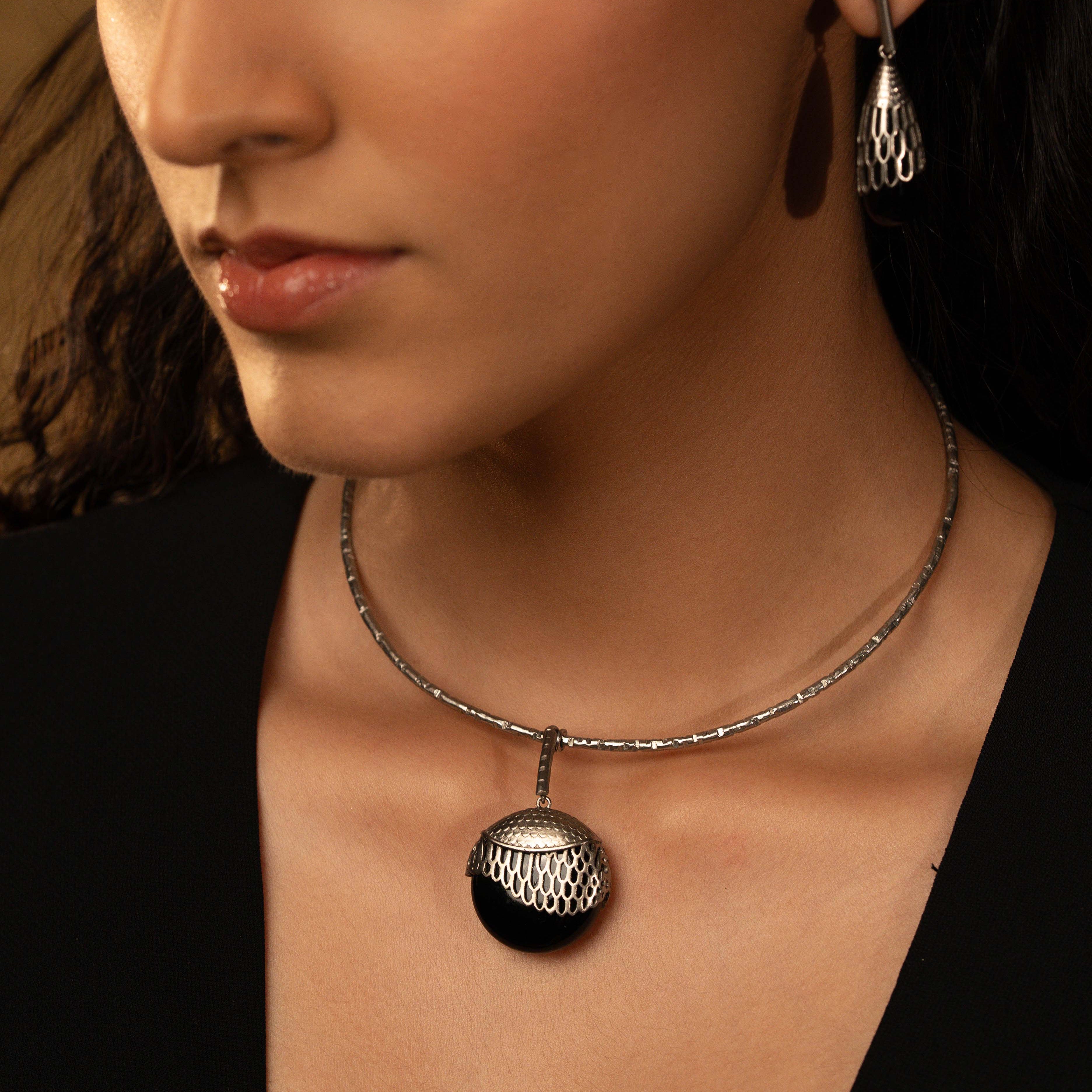 Close-up of a woman wearing a necklace with a pendant against a neutral background